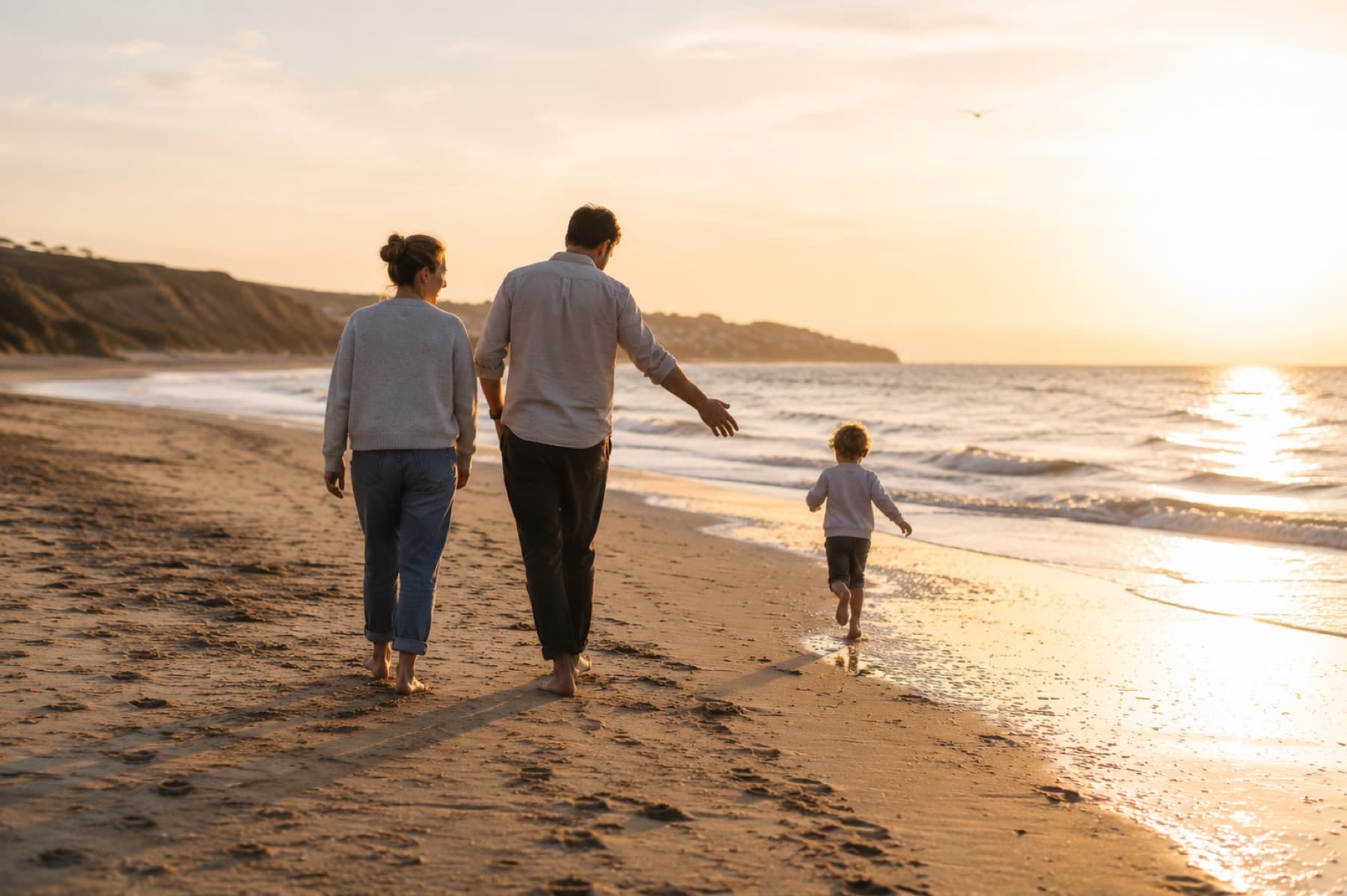 A family walking together beside the sea at sunset